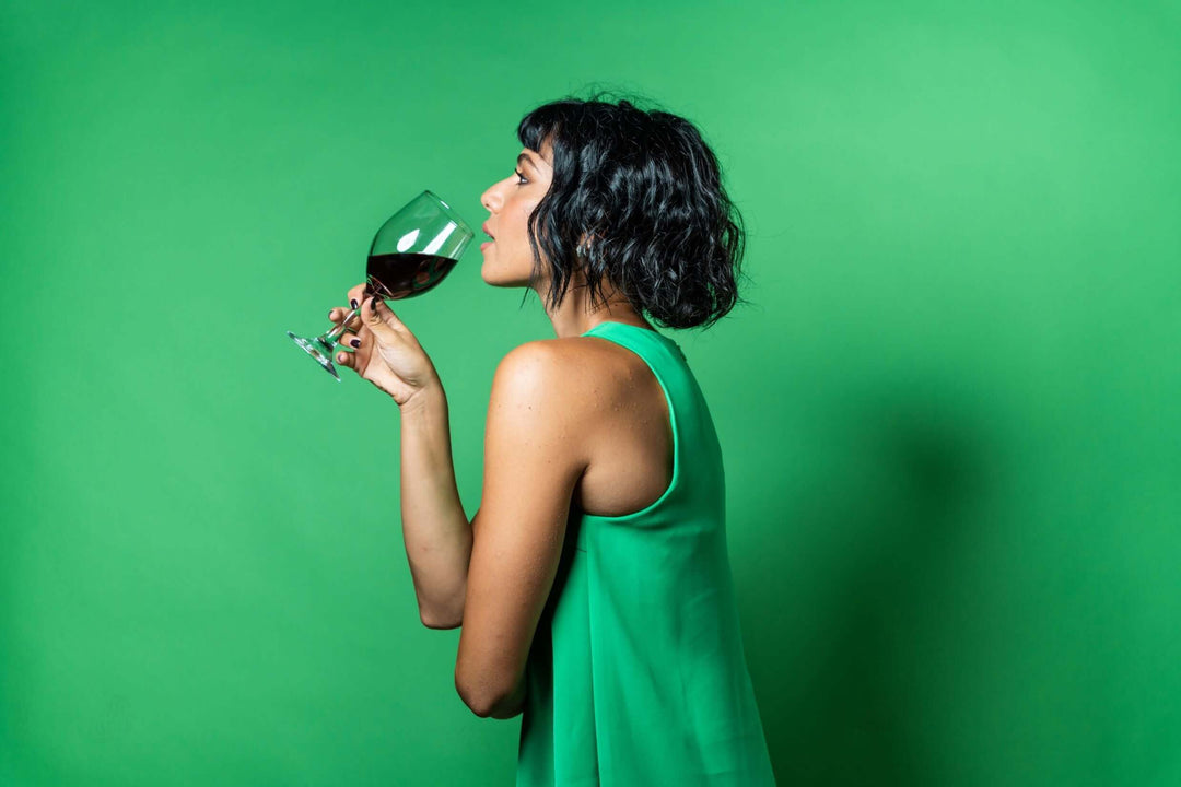 Kvinde i grøn kjole der drikker vin